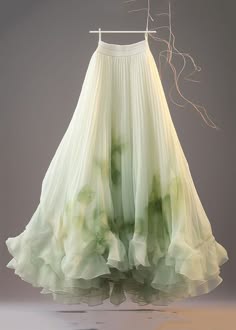 a flowing, pleated, green skirt with a ruffle hem, hanging on a hanger. the skirt is made of a soft, sheer fabric that drapes beautifully. the skirt is a stunning piece of clothing that would be perfect for a formal event. the fabric appears to be silk or a similar light material.  there are hints of green and brown dye within the fabric that give it a slightly ombre effect. the skirt appears to be handmade and a designer piece. the overall look is elegant and formal.