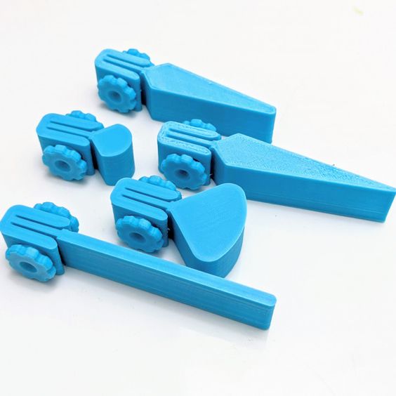 a set of 5 bright blue 3d printed plastic toys that are miniature versions of tools, with each piece having a unique design. they are all laid out on a white surface with a clear view of the detail and intricate designs of each piece. the blue color contrasts with the white background, making the toys stand out.