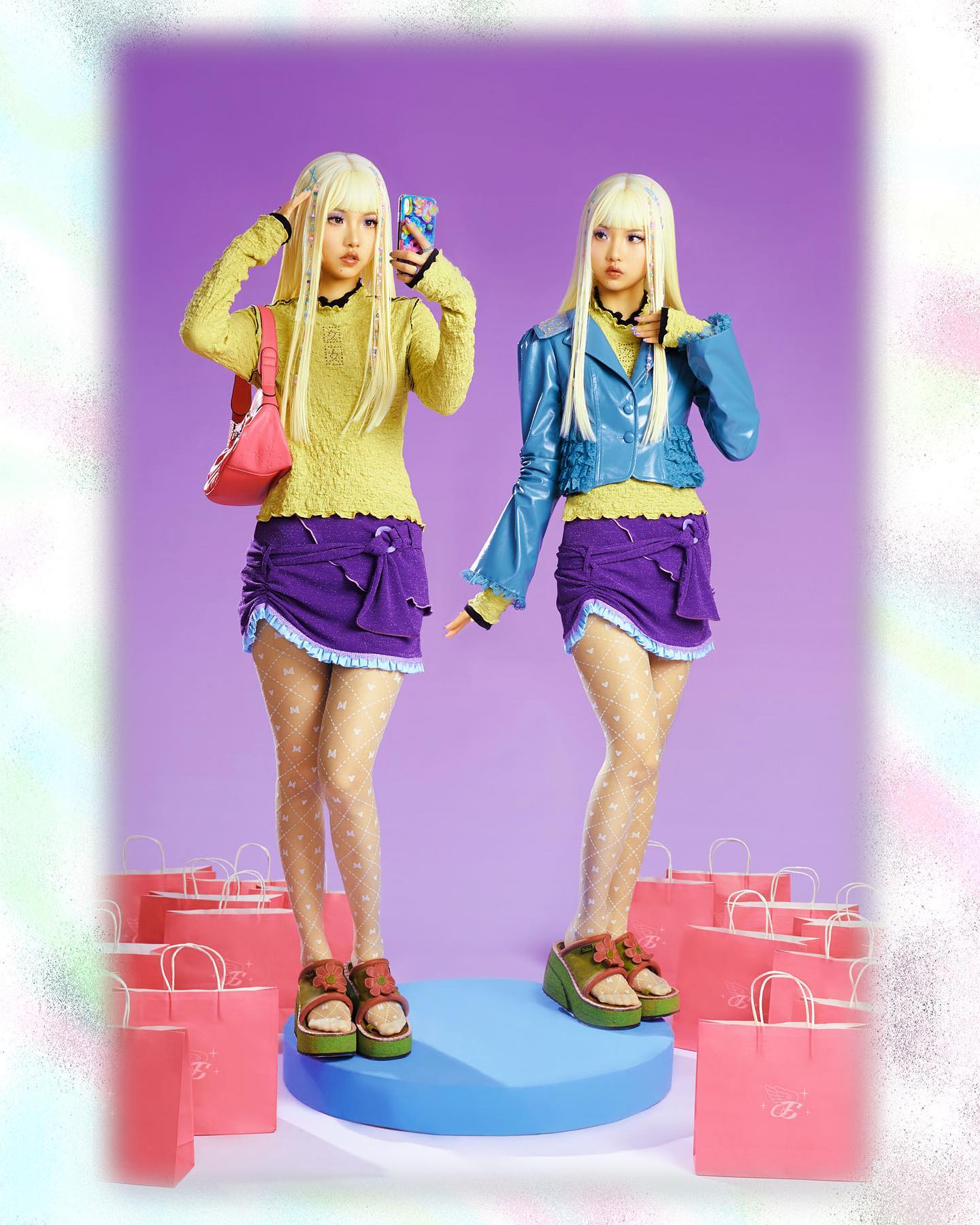 the image features two identical twin girls dressed in coordinated, vibrant y2kinspired outfits.  they are standing against a purple backdrop, surrounded by pastel pink shopping bags.  both girls are blonde, wearing pastelcolored clothing,  including a yellow knitted sweater, a purple miniskirt with ruffles, and fishnet stockings. one twin sports a turquoise cropped jacket. they're both wearing chunky platform shoes. one girl is taking a selfie with a cell phone.  the overall aesthetic is playful, fashionable, and trendy, reminiscent of 90s and early 2000s styles. the bright colors and numerous shopping bags suggest a theme around shopping, fashion, and youth culture. the image likely serves as promotional material for a clothing brand or a similar product.
