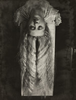 the image is a striking monochrome (black and white) portrait of a woman. she is lying upside down, her long hair cascading down around her,  with fabric draped over and around her body. her expression is serene yet perhaps slightly melancholic.  the background is dark and indistinct, drawing focus solely to the figure. the photographic style suggests a vintage or antique print, possibly from the early 20th century, with a high level of artistic and technical skill evident in the composition and tonal range. the overall mood is mysterious and somewhat ethereal.