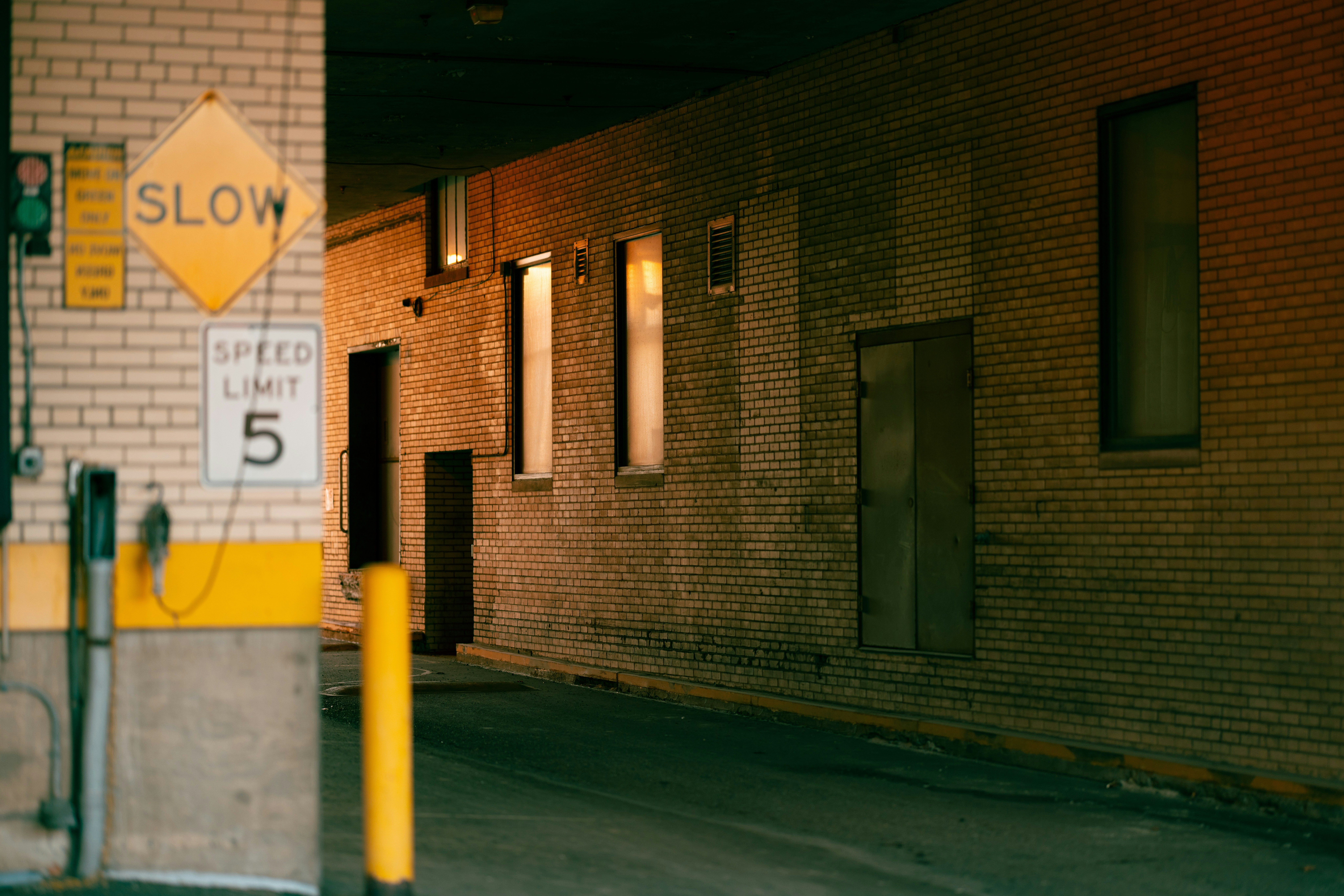 an urban alleyway is bathed in the warm light of the setting sun. the brick walls of the buildings are cast in shadow, creating a moody and atmospheric scene. the focus is on the receding lines of the alleyway, drawing the viewer into the image.