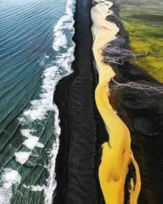 an aerial view of a black sand beach and a yellow river. the beach is on the left side of the image and the river is on the right side. the river is winding through the sand and it is very bright yellow. the beach is very black and the water is very blue. the water is crashing onto the beach and there are waves forming. the sand is very fine and the waves are very big. the water is very clear and you can see the bottom of the ocean. the river is very wide and it is flowing very fast. the water is very clear and you can see the bottom of the river. the sky is very blue and it is very clear.