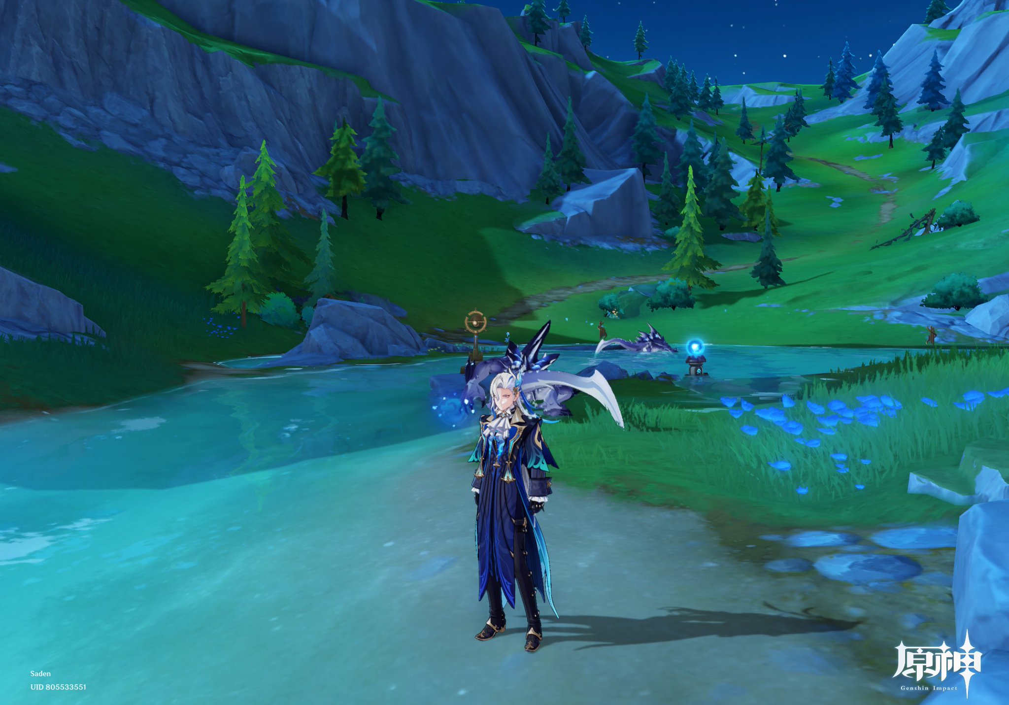 a screenshot from the video game genshin impact shows a male character, saden (uid 805533551), standing by a calm river at night. the character is wearing a detailed blue and black outfit. the background features a serene landscape of rolling green hills, dark rocky cliffs, and lush forests under a starry sky.  glowing blue flowers and water effects add a mystical atmosphere.  other players or their characters can be seen in the distance.  the genshin impact logo is visible in the bottom right corner.