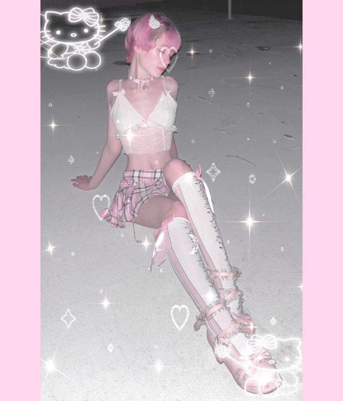 the image depicts a young woman styled in a pastel pink, kawaiiinspired outfit.  she has short, pink hair and is wearing a pink and white lace crop top, a plaid pink mini skirt, and matching laceup kneehigh socks and boots.  the overall aesthetic is a blend of sweet lolita and possibly elements of gothic lolita fashion, incorporating elements that are both cute and slightly darker. the photo is edited with a soft focus and a glitter overlay, adding to the dreamy, whimsical feel. hello kitty graphics are digitally added to the image, reinforcing the kawaii theme. the setting appears to be outdoors at night.  the model is posed casually, sitting on the ground.