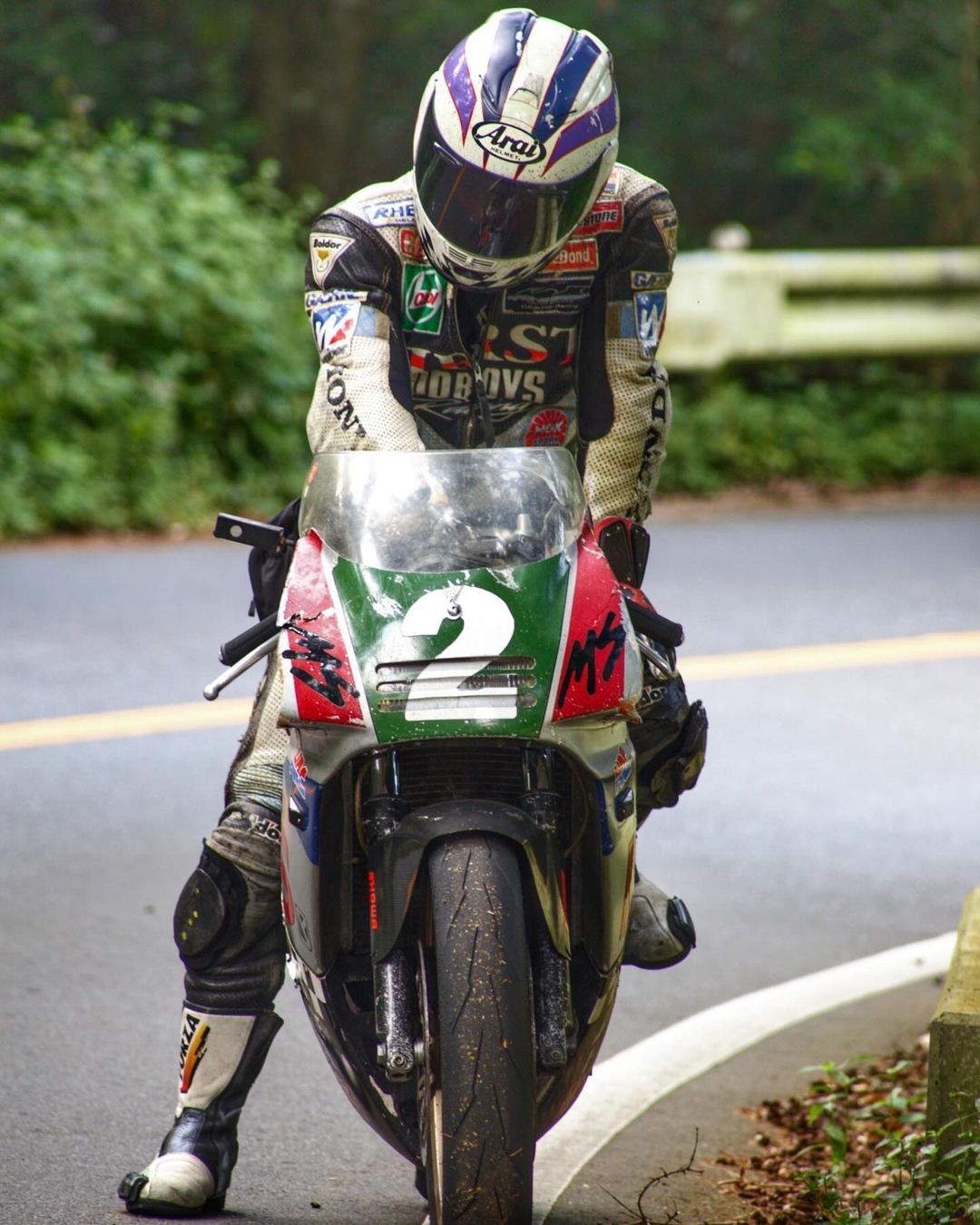 a racer on a motorcycle, wearing a helmet and leathers, prepares to take on a race track. the rider has a determined look in their eye, and the motorcycle is ready for the challenge.