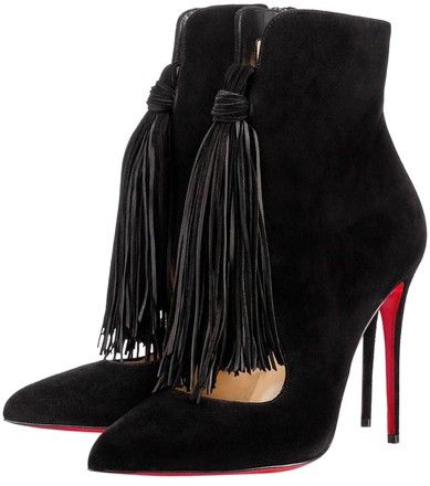 the image shows a pair of black suede ankle boots with long black tassels adorning the sides. the boots have a pointed toe and stiletto heels with characteristic red lacquered soles, reminiscent of christian louboutin's style.  they appear to be made of highquality material and have a sophisticated, elegant design suitable for formal occasions or special events.