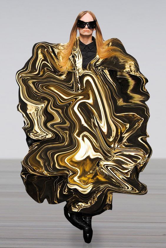 a female fashion model wearing a striking golden metallic dress that swirls and flows, like liquid gold. she is posing on the runway, her hair cascades around her shoulders and she is wearing black sunglasses. the dress is an interesting mix of textures and abstract shapes, making it a very avantgarde piece. it's a fashion show with a dramatic touch.