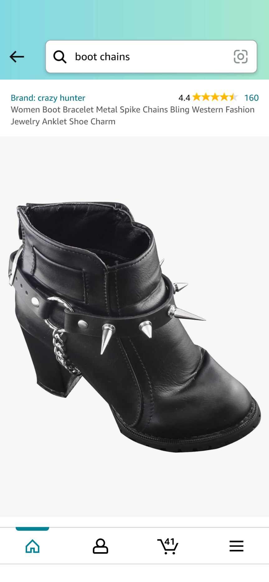 a black ankle boot with metal spike chains, a bling western fashion jewelry anklet shoe charm.  the boot is made of faux leather and has a chunky heel. the ankle chain is made of metal and has spikes. the chain is connected to a metal clasp. the boot is perfect for a punk or gothic look.