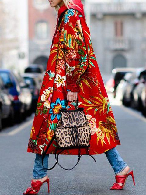 a fulllength shot of a fashionable woman walking down a city street. she is wearing a long, red floralprint coat, blue jeans, and red high heels. she carries a leopard print backpack. the overall style is trendy and stylish, perfect for autumn or winter. the background is slightly blurred, focusing attention on the woman and her outfit.