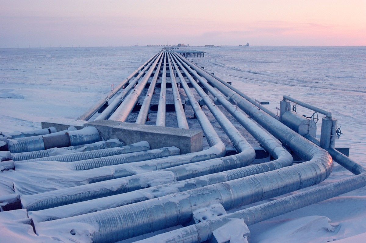 a long, winding pipeline stretches across a vast, snowy landscape under a pale pink sky. the pipes are made of metal and are arranged in a parallel fashion, creating a sense of endlessness. the snow is deep and pristine, and the only sign of life is the pipeline itself. the image evokes a sense of isolation, harshness, and the power of human ingenuity in the face of nature's challenges. the pipeline likely transports oil or gas, symbolizing the vital role of energy resources in modern society. the image captures the stark beauty of the arctic environment and the engineering feats required to extract resources from such remote locations.