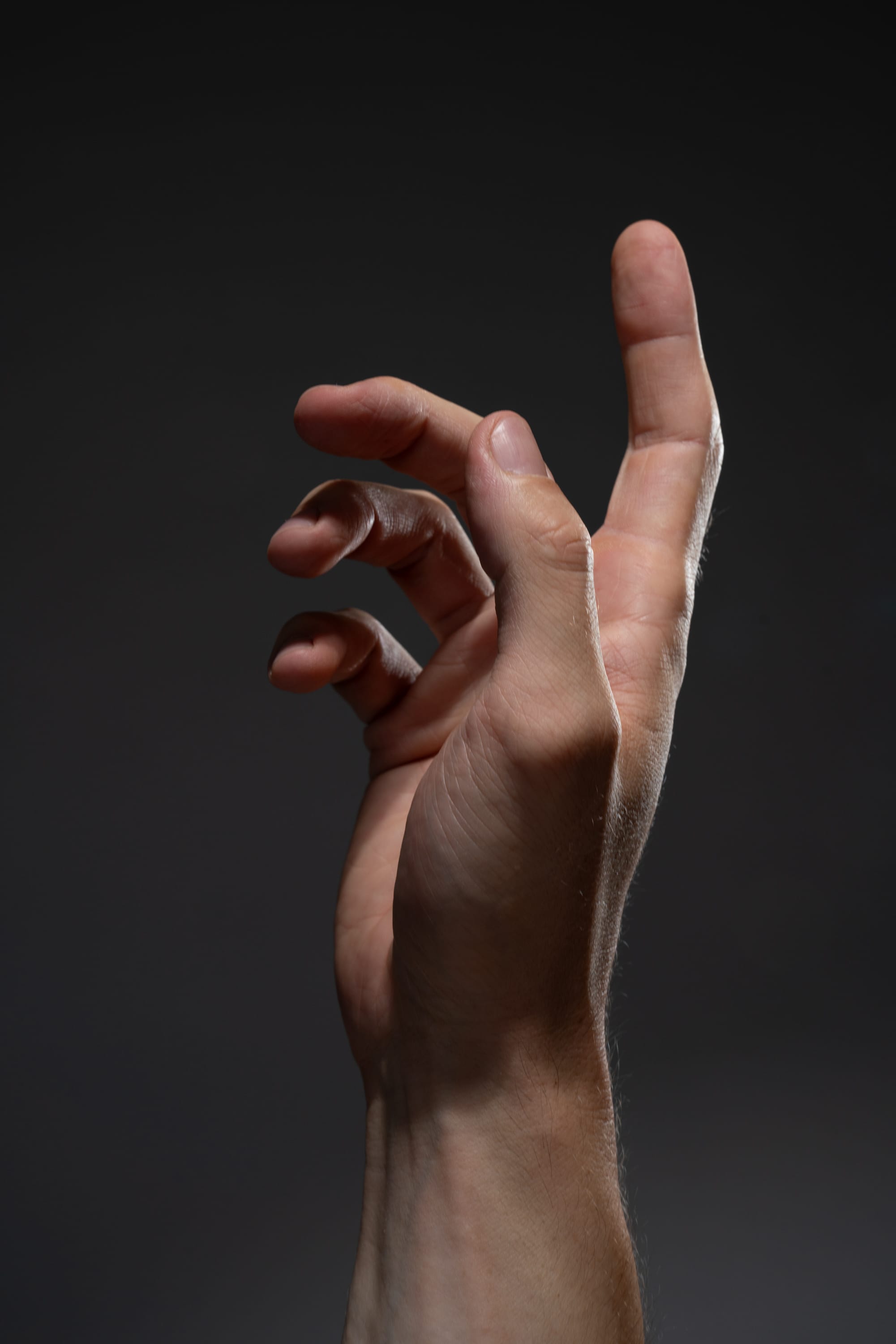 a man's hand reaching upward against a dark background. the lighting emphasizes the texture and shape of the hand, creating a dramatic and expressive image.