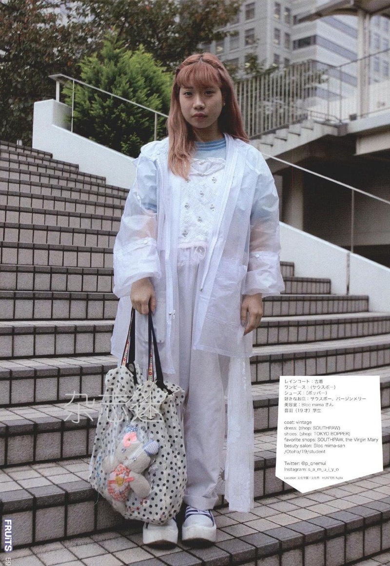 a young woman is standing on a set of stairs, posing for the camera.  she is wearing a white raincoat, a white dress, and white shoes.  her pink hair is long and straight.  she is carrying a large polkadotted tote bag that has stuffed animals attached to it.  the text to the right of the image is in japanese, with the exception of some store and brand names.