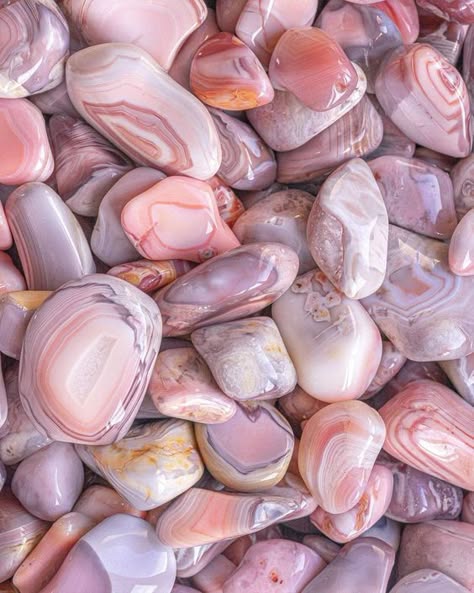 a closeup image of a collection of pink agate and rose quartz stones. the stones are polished and smooth, and the image shows the intricate patterns of the stone. the image is taken from a macro perspective, showing the detail of the stones.  the colors range from pale pink to deep rose, and the stones are arranged in a random pattern. the image is lit from above, casting a soft glow on the stones.