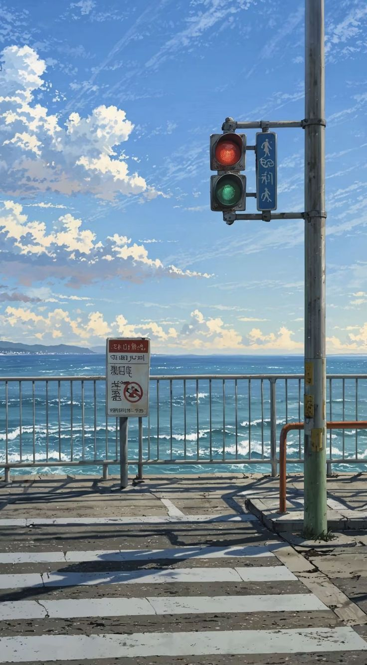 an eyelevel shot shows a crosswalk near an ocean. a traffic light is on a pole on the right, and the light is red. to the left of the traffic light is a sign with an image of a person walking. a nosmoking sign is attached to the rail in front of the ocean. the sky is blue with white clouds.
