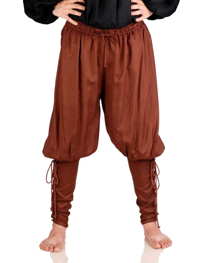 a person is wearing renaissancestyle brown, baggy trousers with lacing at the ankles. the pants have a drawstring waistband and a loose, gathered fit. they are barefoot. the person is wearing a black top and has their hands on their hips. the background is a plain white.