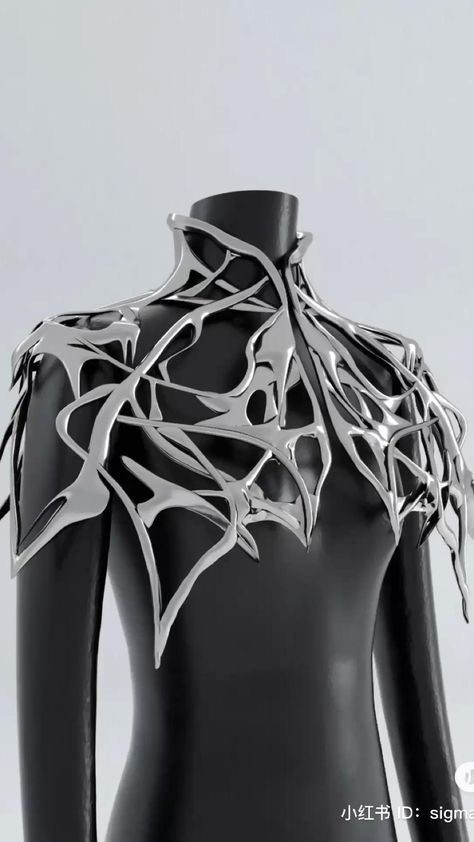 he image showcases a striking, metallic shoulder piece sculpted in an intricate, abstract design. the piece resembles a stylized, fragmented web or perhaps a futuristic interpretation of armor. the material appears to be polished silver, reflecting the soft light of the studio setting. it is displayed on a featureless black mannequin, emphasizing the dramatic form and craftsmanship of the artwork.