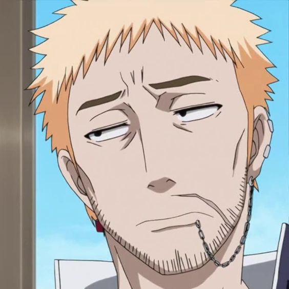 the image is a portrait of a blonde haired man with a bored or unimpressed facial expression.  he has short blonde hair, stubble, and is wearing an earring and a small chain around his neck.  the lighting is soft and the background is blurred.