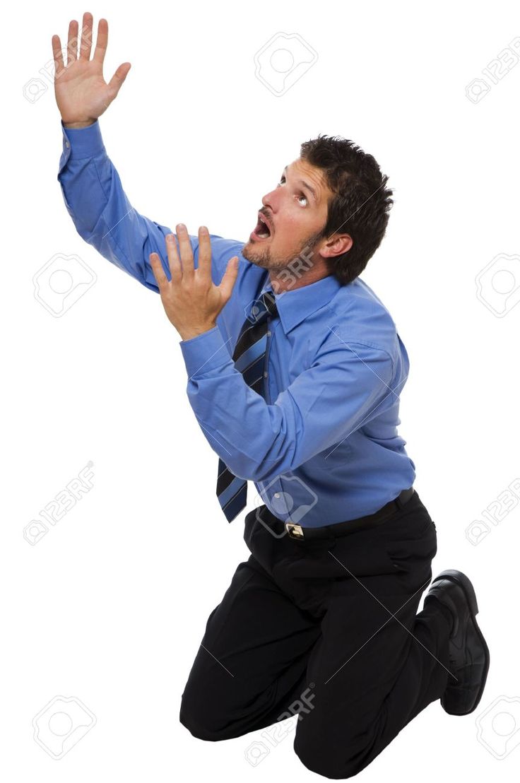 a fullbody shot of a businessman kneeling on a white background, his hands raised in a gesture of pleading or desperation. he appears shocked or scared, with a look of worry and anxiety on his face. he is dressed in a blue shirt, black pants, and a tie, typical business attire. the image suggests a sense of urgency or a dire situation.  the background is plain white, isolating the subject and emphasizing his emotional expression.