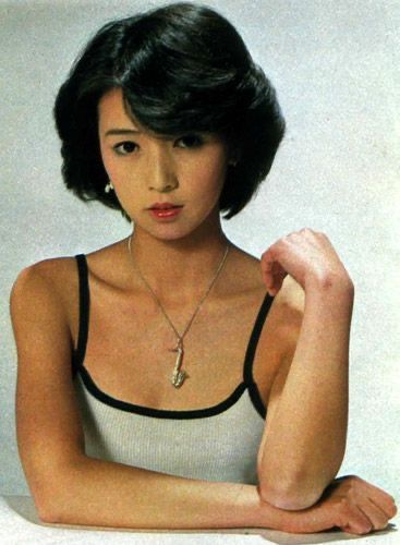 a portrait of a young japanese woman with short black hair, wearing a sleeveless white tank top with black trim and a silver necklace with a pendant, smiling slightly at the camera.