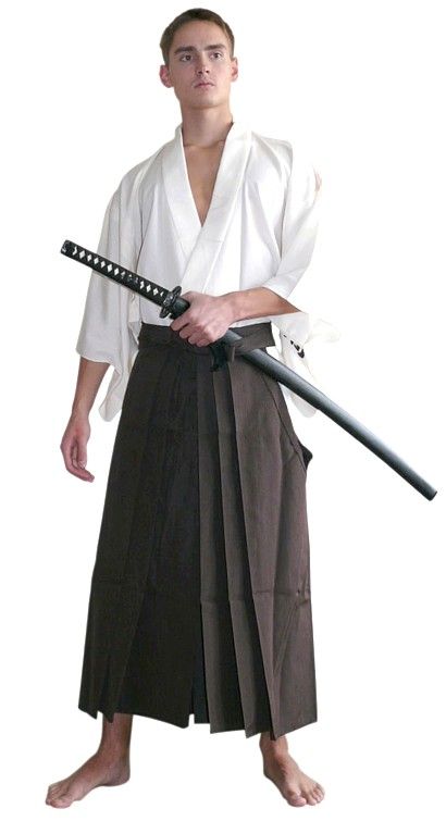 a man dressed in a white hakama and brown hakama pants, with a katana in his hand, looks to the left of the camera.
