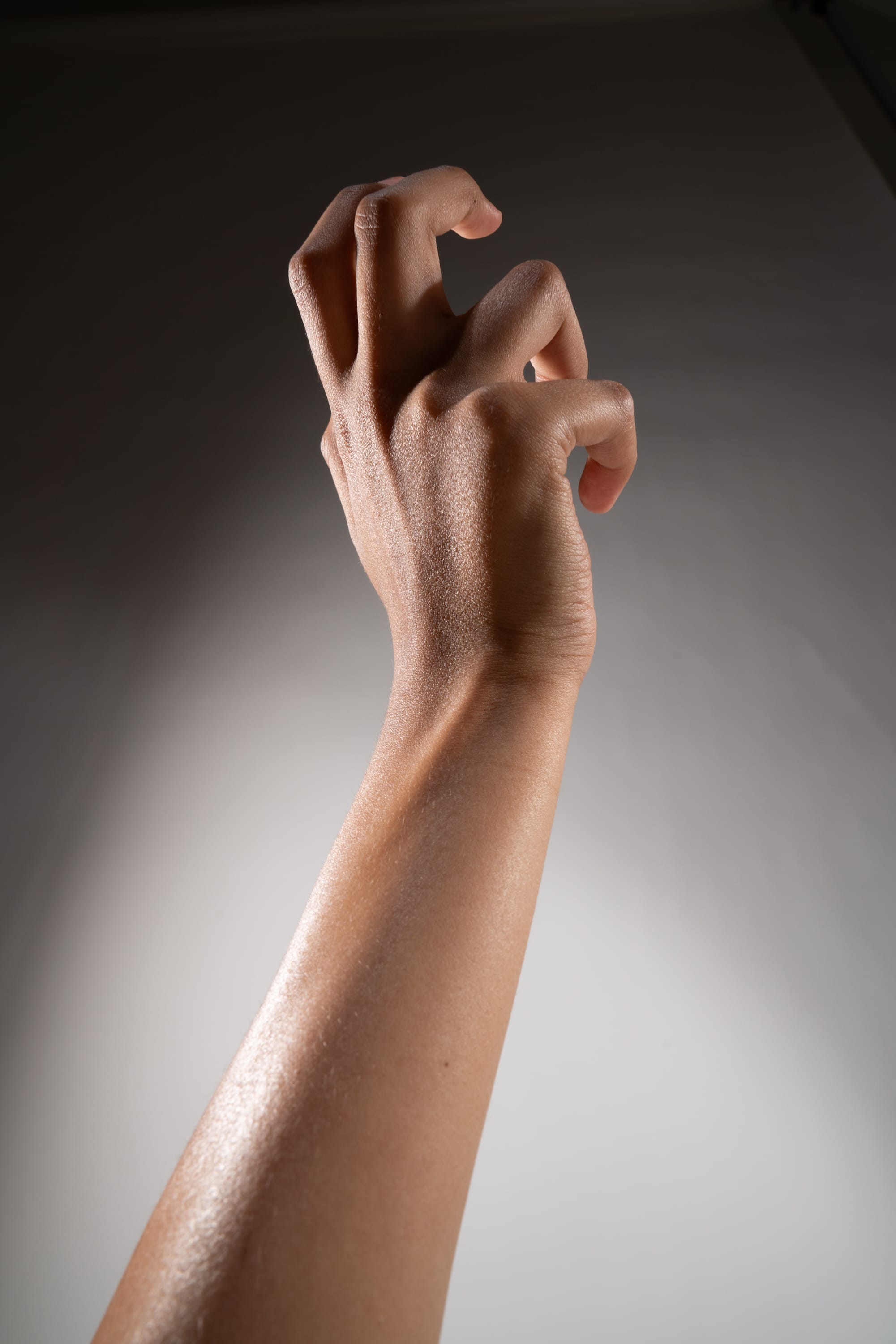 a closeup shot of a hand reaching upwards. the hand is illuminated with soft studio lighting, highlighting the texture and contours of the skin. the perspective is from below, creating a sense of power and dynamism.