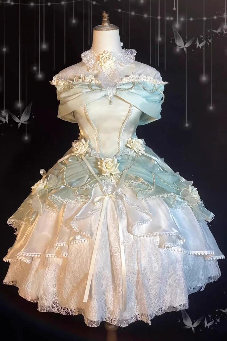 this image showcases a stunning lolita fashion dress. the dress is a beautiful blend of mint green and cream, with intricate lace and tulle details. the bodice is fitted, with a sweetheart neckline and offtheshoulder sleeves. it is adorned with delicate lace, bows, and flower embellishments. the skirt is full and flowing, with layers of tulle and lace creating a dreamy and romantic silhouette. the dress is displayed on a mannequin against a dark background with twinkling lights and butterfly decorations, further enhancing its enchanting aura.