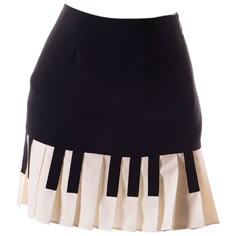 a black skirt with white ruffles that resemble piano keys. the skirt is a highwaisted style with a straight silhouette. the ruffles are at the bottom of the skirt and extend slightly beyond the hemline. the skirt is made of a smooth fabric and appears to be of good quality.