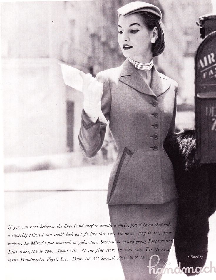 a vintage advertisement for a handmachervogel tailored suit. the image shows a woman wearing a fitted jacket, skirt, gloves, pearls, and a hat. she is holding a letter and standing next to an air mail mailbox. the advertisement text describes the suit's features, including long jacket, spear pockets, and materials such as miron's fine worsteds or gabardine. it also mentions sizes and price.