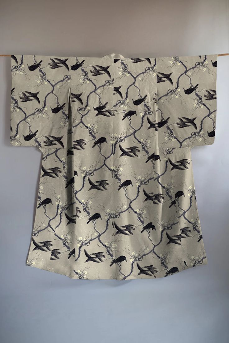 a kimono with a bird and branch pattern is displayed hanging on a rod.
