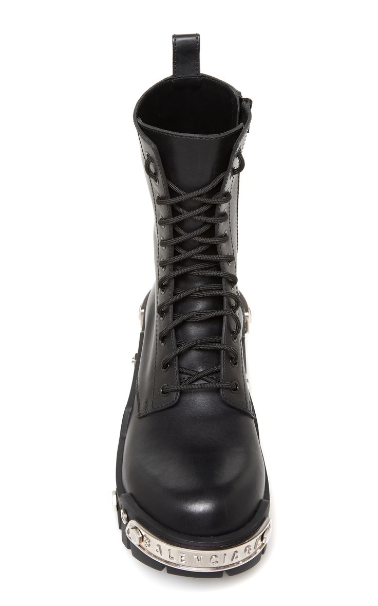 a closeup studio shot of a pair of balenciaga black leather combat boots. the boots are laceup style with a platform sole and metal detailing around the sole and heel.  the boots are shown from a slightly elevated angle, showcasing their features. the background is plain white, focusing all attention on the boots.