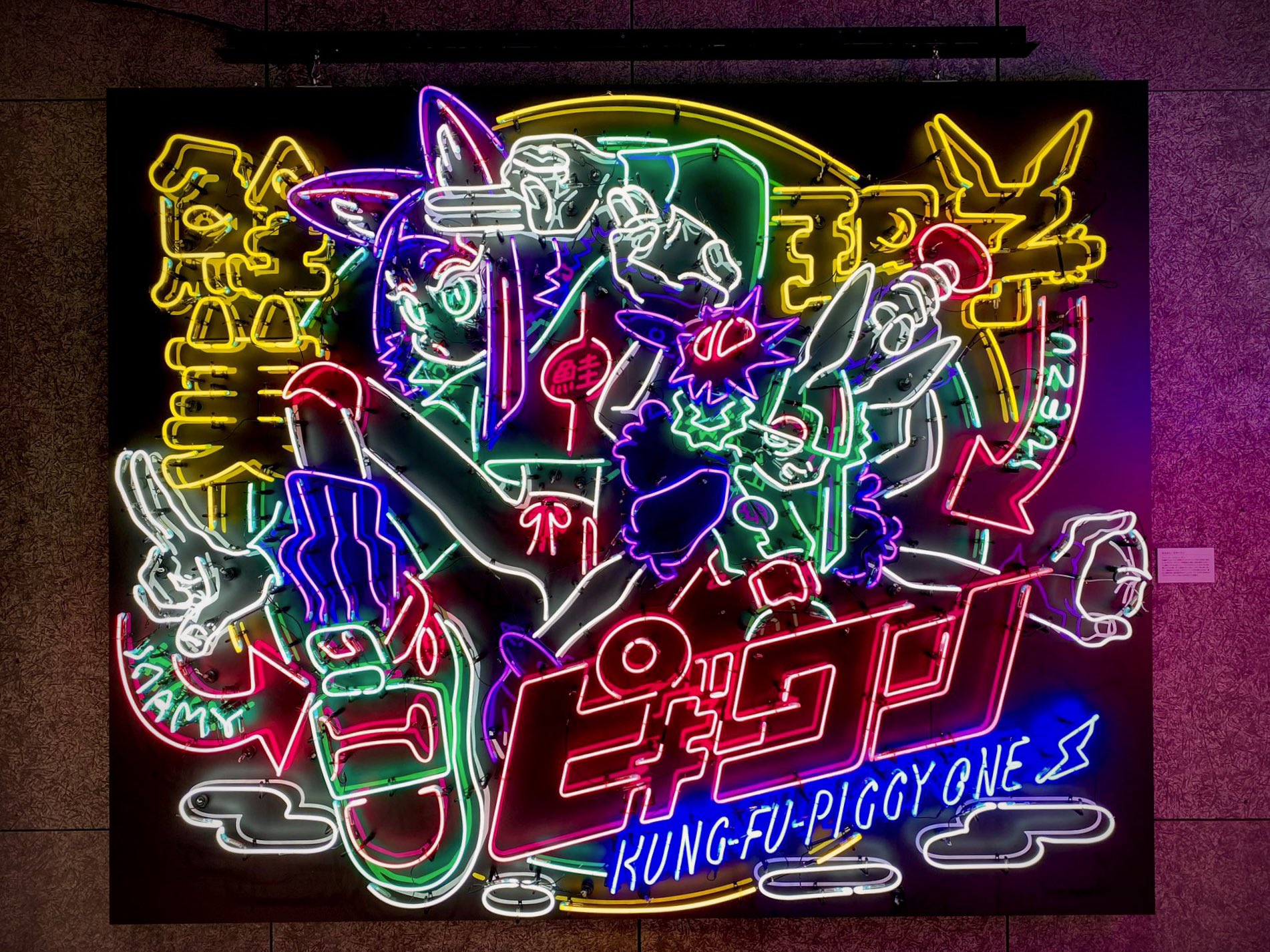 a vibrant neon sign depicting cartoon characters in a dynamic, actionoriented scene. the style is reminiscent of anime and manga, with exaggerated features and bold lines. the sign is set against a dark background, making the neon colors pop. chinese characters are integrated into the design, adding to the cultural fusion aesthetic. the text "kungfupiggy one" is prominently displayed, suggesting a movie or video game title.