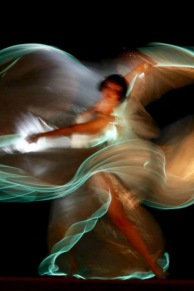 a woman in a flowing white dress dances gracefully, her body a blur of motion as she twirls. the dress catches the light, creating an ethereal glow that makes her appear almost magical.