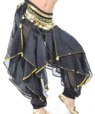 a woman wearing black harem pants with gold trim and a coin belt is pictured. the pants are layered and have ruffled edges, and the fabric appears to be sheer in some areas. the woman is also wearing shiny gold flats.