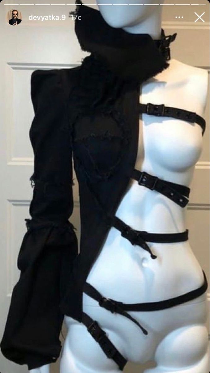 a fashion model wearing a black and white outfit. the outfit is made up of a black jacket with straps, a white body harness, and black straps over a white body suit.