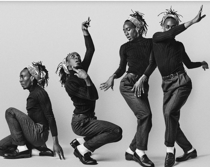 four dancers in black and white, each striking a unique pose,  they wear black turtlenecks, gray pants, and black shoes. their expressions are intense, and their bodies are stretched in dynamic positions. they are in a studio setting, and the monochrome aesthetic adds to the sense of drama.