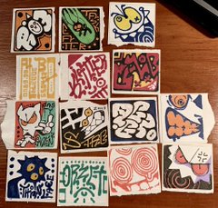 a top down view of sixteen colorful stickers with various doodle art on them. the stickers are laying on a wood table.