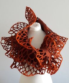 a close up of a beautiful orange wool scarf with an intricate design. it's made with a felt like material, creating a delicate and intricate collar.
