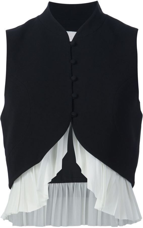 a black sleeveless vest with a white ruffled bottom. the vest has a mandarin collar and is fastened with buttons. the ruffle is layered and gives the vest a more feminine look.