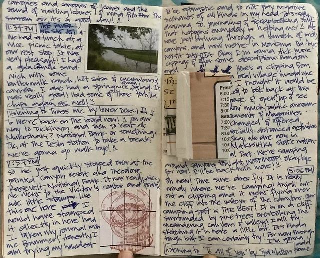 the image shows a twopage spread from a travel journal. the journal entries are handwritten in blue ink. the left page features a photo of a green landscape taken from a car window. the journal entry describes a stop at a picnic table and mentions the name of the "the paver," presumably a river or a restaurant. the right page features multiple entries. the top entry is about trying to avoid negative thoughts. below that, a clipping is pasted with a schedule of activities for a nearby village called "focal." the bottom entry describes the current location: "makoshika state national park," and the excitement of camping in a windy area with amazing views. the journal entry concludes with the phrase "to all of you by syd matters fame," suggesting that the writer is sharing their travel experience with others.