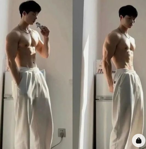 the image features a muscular young man in white sweatpants standing in a kitchen. the man is shirtless and is flexing his arm muscles. the image is split into two, showcasing different poses from a side perspective. the kitchen is simple with a white refrigerator prominently displayed. natural sunlight illuminates the scene.