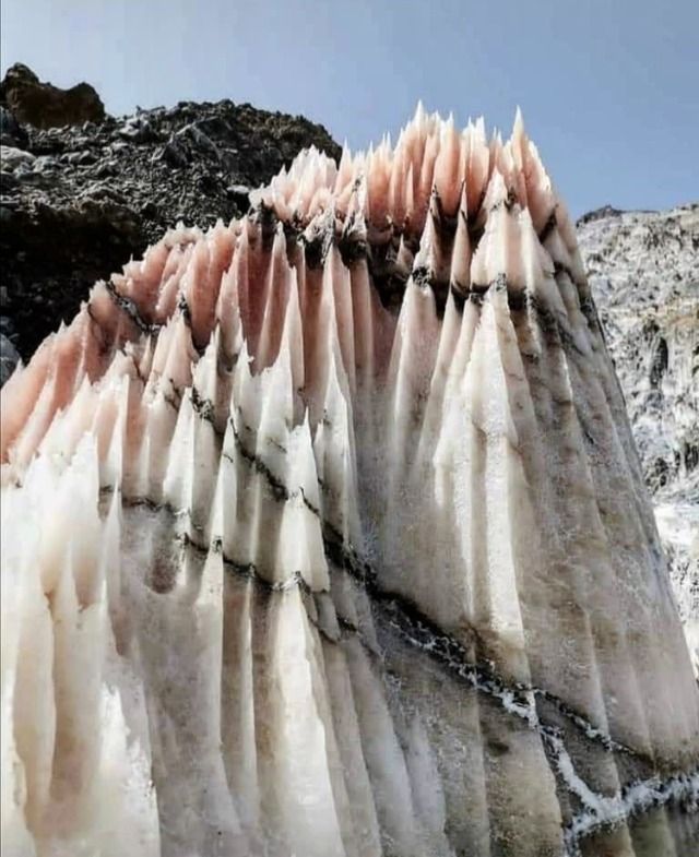 a closeup image of a salt mountain with pink and white stripes. the salt formation resembles a castle with tall towers, highlighting the beauty and wonder of nature. the texture and pattern are captivating and create a sense of grandeur.