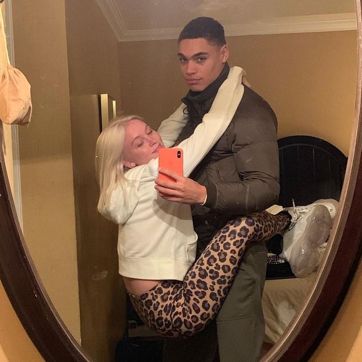 a man and a woman are looking at each other in a mirror. the woman is holding a cell phone