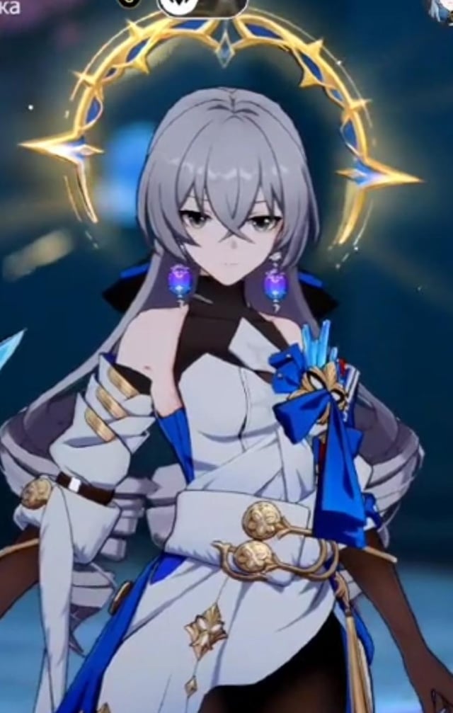 the image shows a female character from the video game genshin impact. she has long, flowing white hair and is wearing a stylish outfit predominantly white and blue with gold accents. the outfit appears elegant and detailed. she is posed standing with a calm but serious expression, and there is a glowing golden and blue halolike design behind her head, suggesting magic or special abilities. the overall style is animeinspired, with vibrant colors and detailed character design.  the image looks like a screenshot from the game itself or official promotional material.