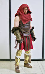 a fullbody shot of a person in a meticulously crafted spartan or roman warrior costume. the costume includes a red hooded cloak, brown leather armor, gold greaves (leg armor), fur arm guards, and a short, pleated red skirt. the individual is standing on a white background.  the detail in the costume is remarkable, suggesting it's a highquality cosplay or historically accurate recreation. the pose and expression are serious, fitting the warrior persona.