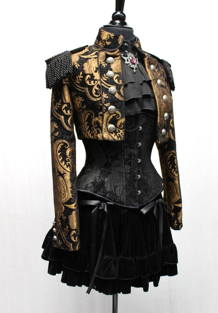 a black and gold women's outfit in a gothic/steampunk style. the outfit consists of a short jacket with gold trim, a corset, and a black velvet skirt with ruffles. the jacket is adorned with intricate details, such as gold buttons and a black braided strap. the corset has a black fabric with a subtle pattern, and the skirt is layered with ruffles. the outfit is complete with a black lace shirt. this outfit is perfect for a formal occasion or a night out.