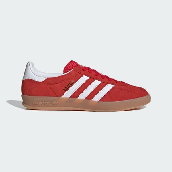 a pair of red adidas gazelle sneakers with white three stripes and a gum sole.