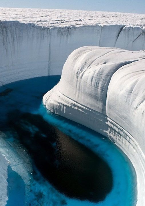 an aerial view of a glacial lake in a crevasse of a glacier. the lake is a deep blue color, surrounded by white snow and ice. the glacier is a vast and powerful force of nature, and the lake is a testament to the beauty and power of the natural world.