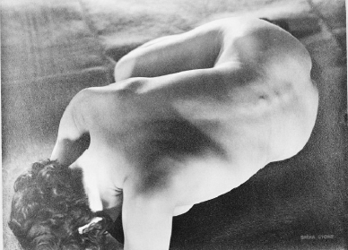 the image is a black and white photograph of a nude female figure.  the subject is positioned in a crouched or fetallike pose, her back arched and her head turned downwards. the focus is on the curves and contours of the body, with strong contrasts between light and shadow highlighting the musculature and form. the overall aesthetic is artistic and somewhat abstract, emphasizing the sculptural quality of the human form rather than specific anatomical details. the grain and texture of the photograph add to its evocative quality.  the background is dark and indistinct, drawing the viewer's attention to the figure.