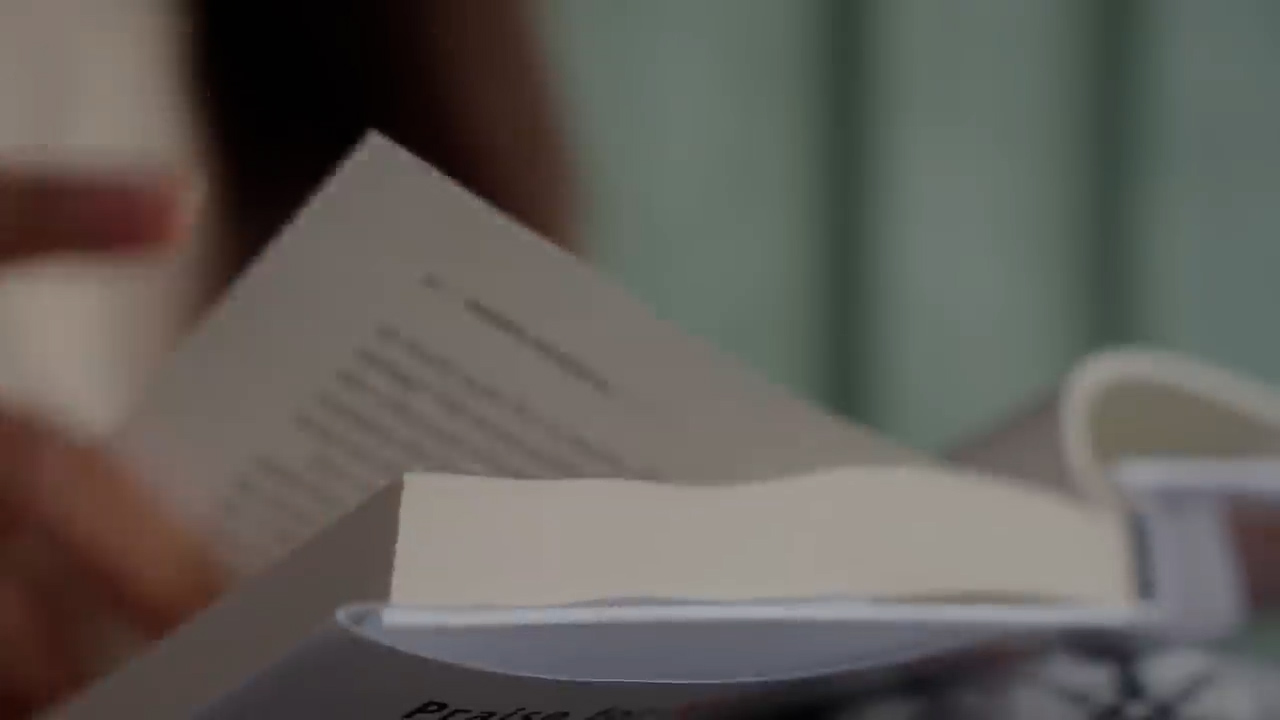 the image shows a closeup view of a person's hands holding a book. the person is in the process of turning the page. the background is blurred, suggesting that the focus is on the act of reading. the soft, natural lighting creates a calm and inviting atmosphere.