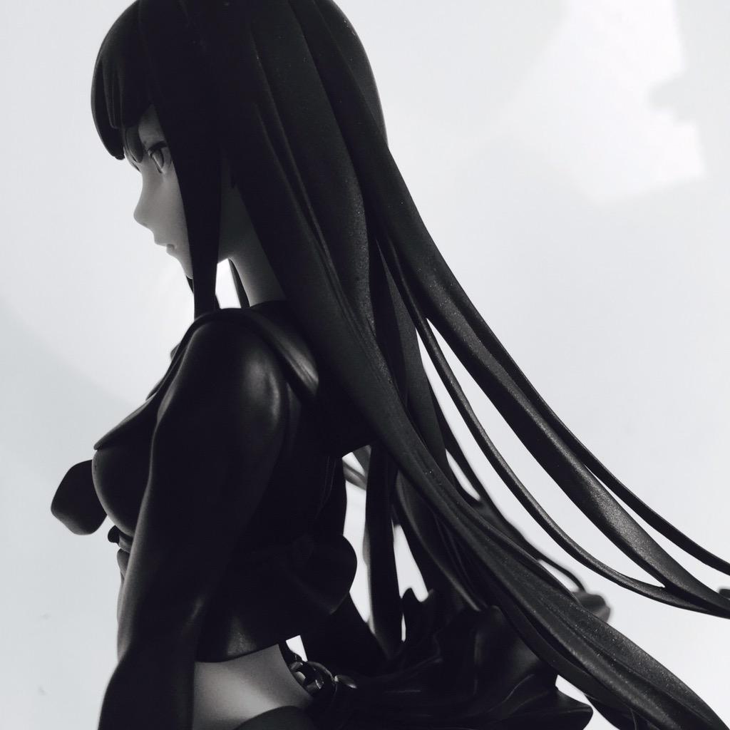 this is a black and white image of a female anime figurine. she's wearing a sailor uniform with a short skirt and her very long dark hair flows behind her. only her side profile is visible, showing her looking off to the left side of the image with a serious expression on her face. the background is a very light gray, providing little contrast from the dark figure.